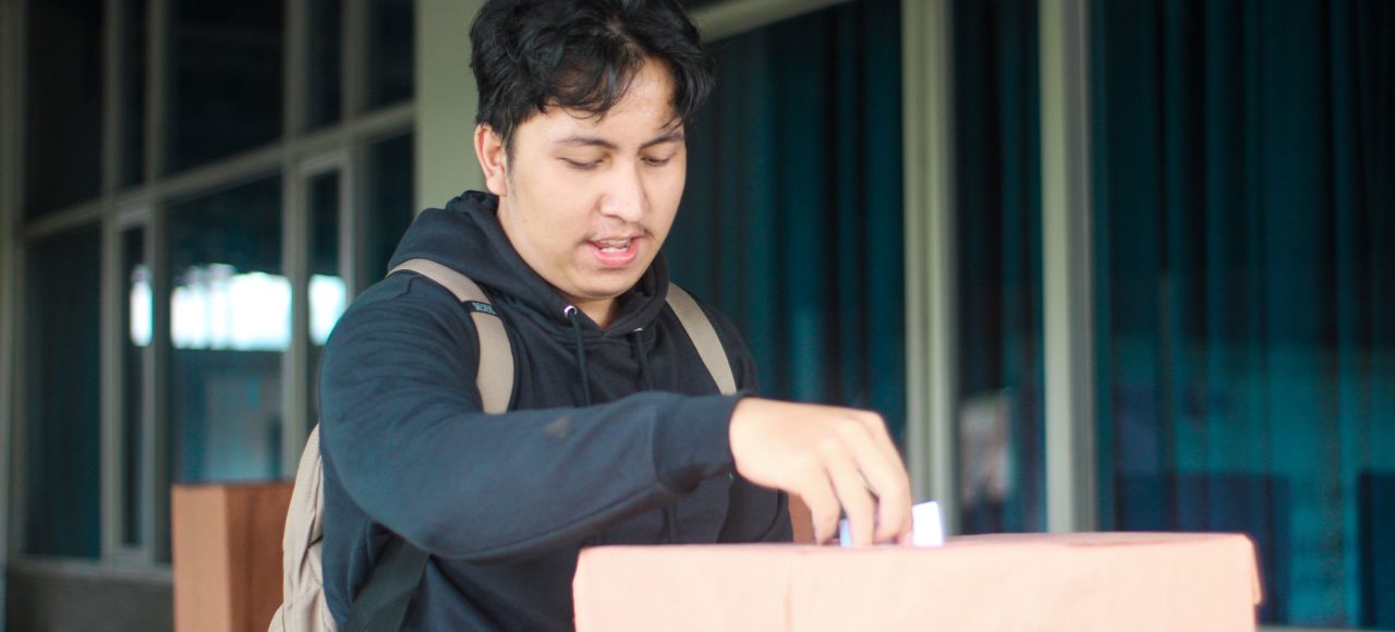 Seorang mahasiswa laki-laki memasukan pillihan dia di acara Pemilihan Mahasiswa Raya 2024