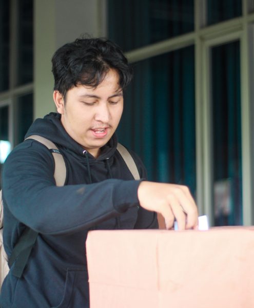 Seorang mahasiswa laki-laki memasukan pillihan dia di acara Pemilihan Mahasiswa Raya 2024