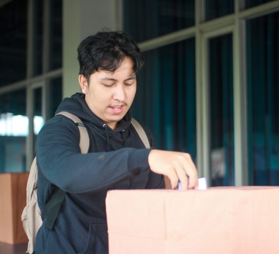 Seorang mahasiswa laki-laki memasukan pillihan dia di acara Pemilihan Mahasiswa Raya 2024