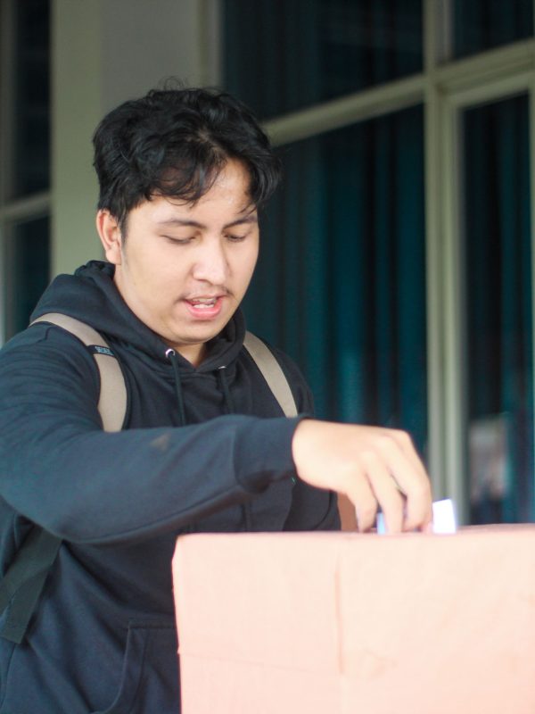 Seorang mahasiswa laki-laki memasukan pillihan dia di acara Pemilihan Mahasiswa Raya 2024