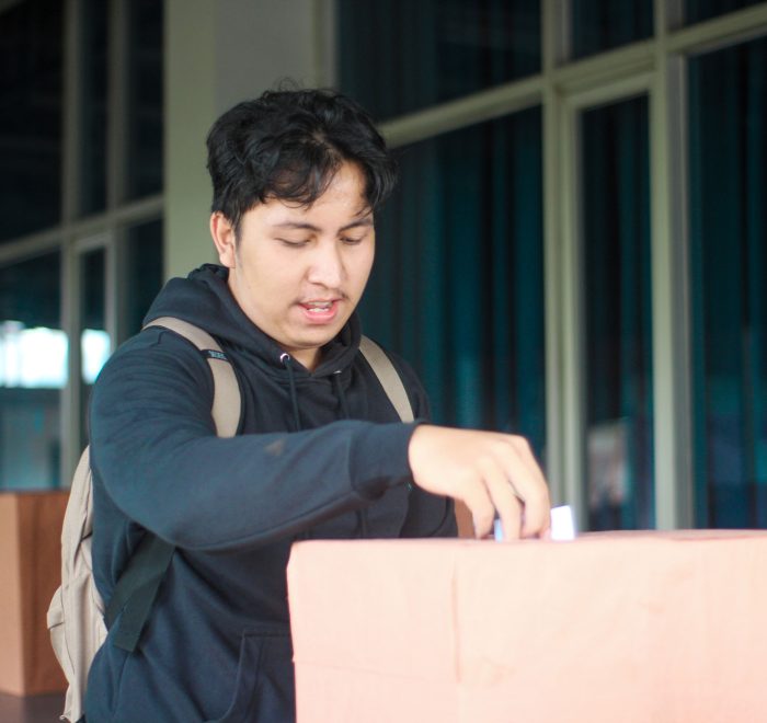 Seorang mahasiswa laki-laki memasukan pillihan dia di acara Pemilihan Mahasiswa Raya 2024
