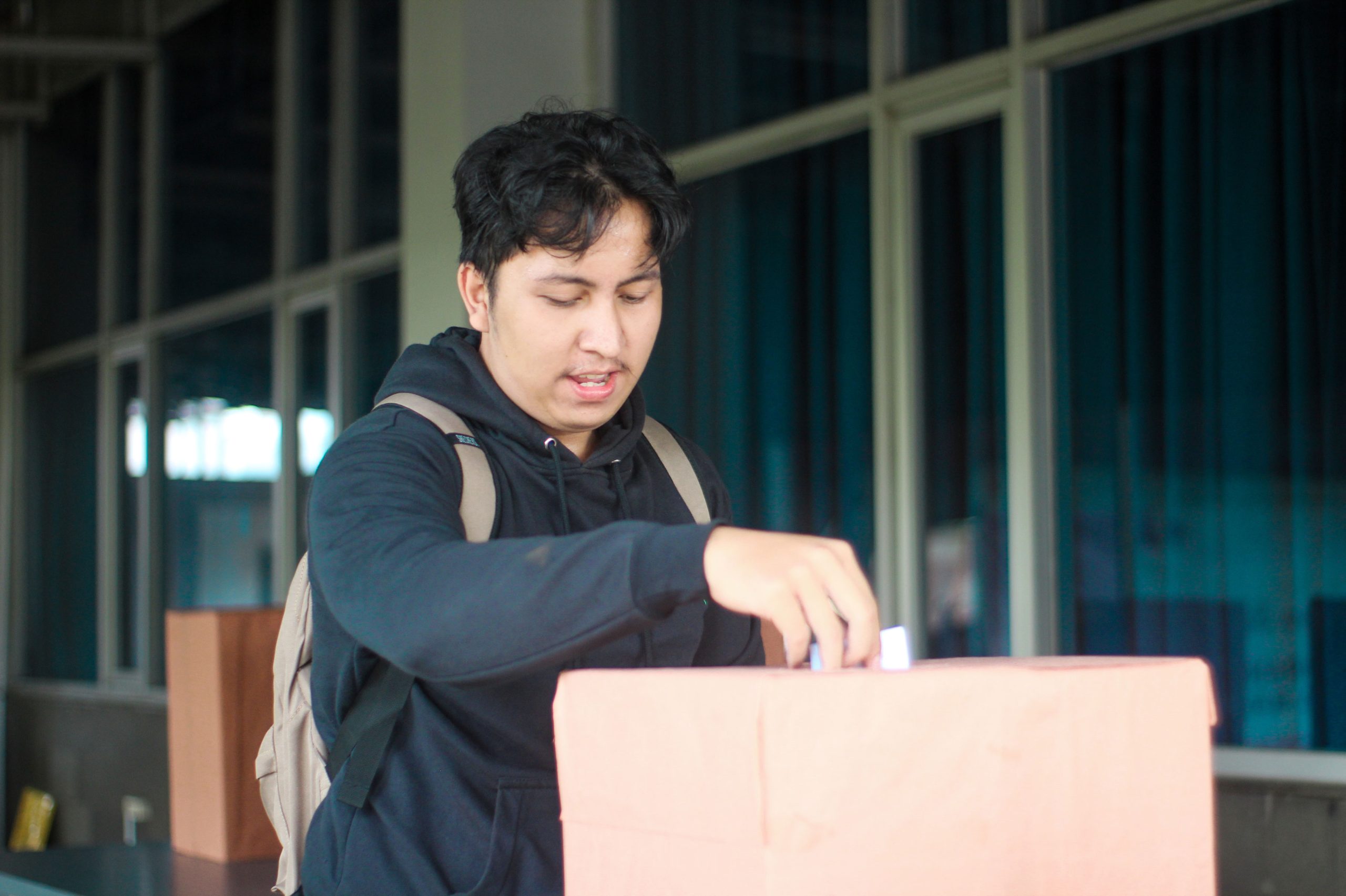 Seorang mahasiswa laki-laki memasukan pillihan dia di acara Pemilihan Mahasiswa Raya 2024
