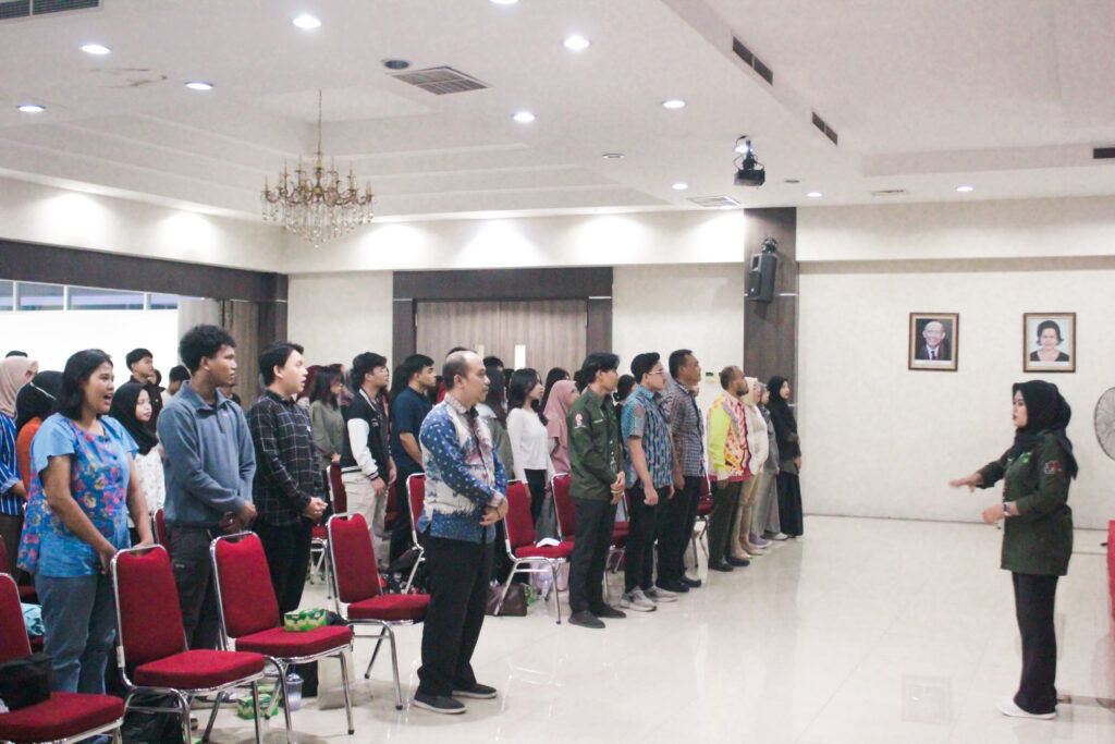 seluruh audience menyanyikan lagu indonesia raya sebagai pembukaan acara sekolah pasar modal 2 di Tri Bhakti